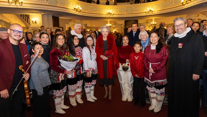 En festlig gruppe poserer sammen i et stort teater iført traditionelt og festligt tøj.