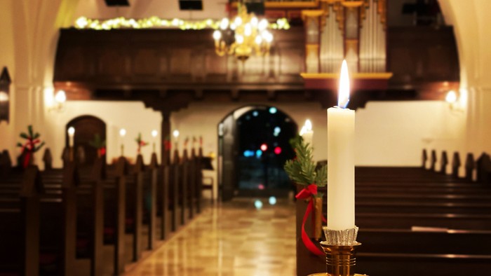 En lysende stearinlys på alteret i en kirke med juledekor.