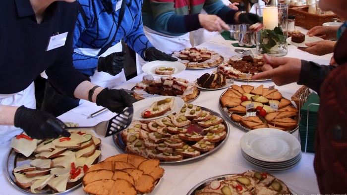 Eine Gruppe von Menschen sitzt an einem Tisch mit verschiedenen Gerichten und Getränken.