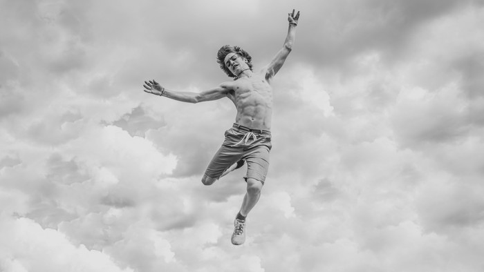 Ein Tänzer schwebt im Himmel mit ausgebreiteten Armen.