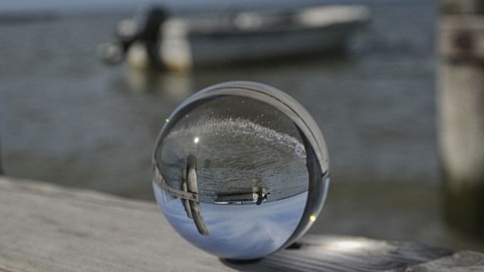 Ein runder Spiegel reflektiert ein Boot auf dem Wasser