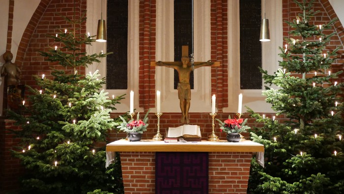 Weihnachtsdekoration in der Kirche mit Krippenfigur und Tannenbäumen