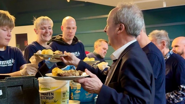 Menschen, die sich am Buffet Essen mit Gewürzen und Tellern selbst bedienen.