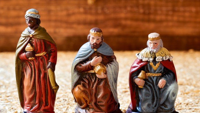 Keramiske krybbefigurer af De Tre Vise Mænd, der knæler med en stjerneformet baggrund.