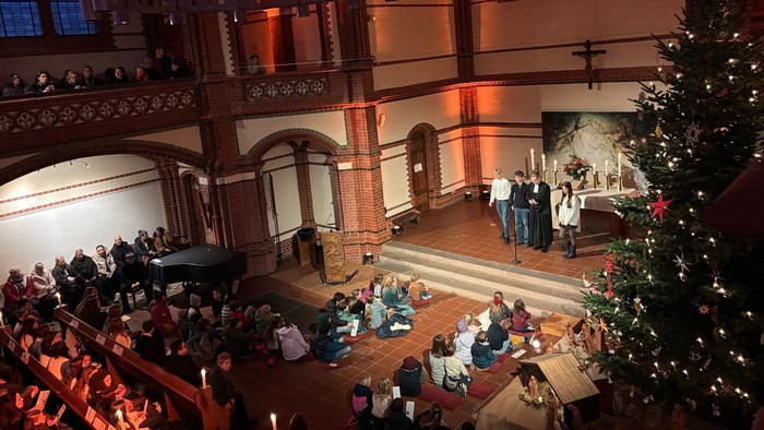 Eine volle und festlich beleuchtete Kirche mit vielen Menschen