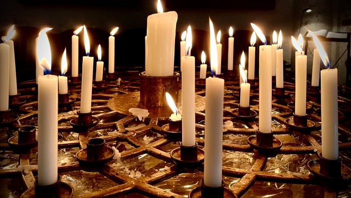 Viele brennende Kerzen auf einem Tisch.