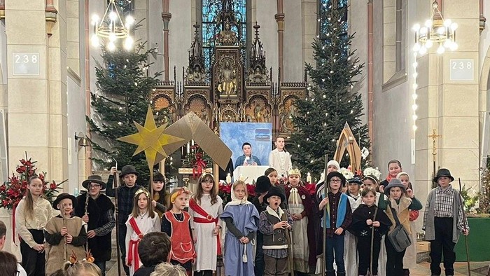 Ein festliches Chorensemble tritt in einer geschmückten Kirche während einer Feierlichkeit im Festtagsgewand auf.