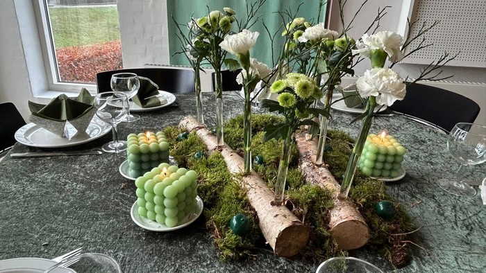 Dækket bord med grønne lys og blomsterdekorationer