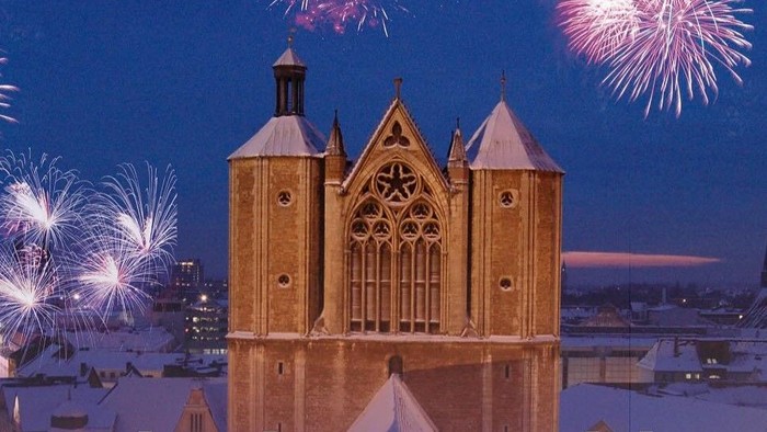 **Silvesterkonzert bei Kerzenschein: Feuerwerk erleuchtet eine verschneite Kathedrale in der Nacht.**