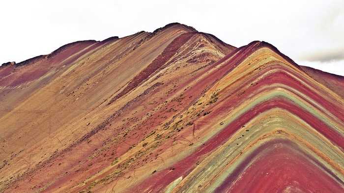 Spektakuläre geschichtete Sedimentfelsen zeigen lebendige rote, orange und gelbe geologische Schichten.