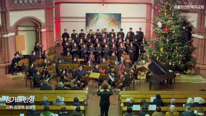 Ein festlicher Kirchenraum, in dem Chor und Orchester unter der Leitung eines Dirigenten vor der versammelten Gemeinde musizieren.