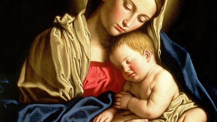 A woman in a golden robe holds a sleeping baby wearing a red garment.