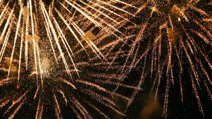 Livlige fyrværkeri eksploderer i gyldne striber mod en mørk nattehimmel.