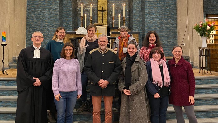Eine Gruppe posiert in einer Kirche mit farbenfrohen Buntglasfenstern und religiösen Dekorationen.