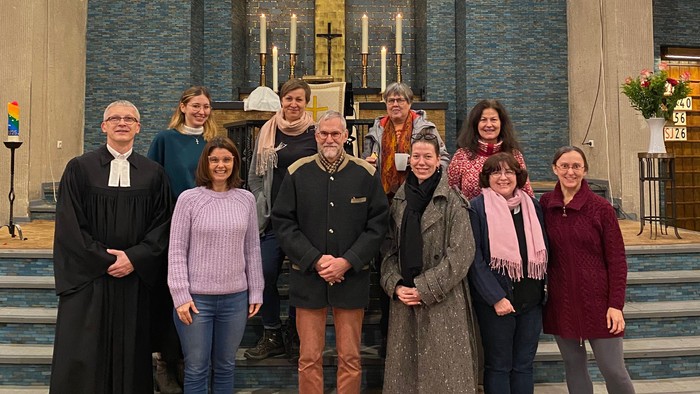 Eine Gruppe posiert in einer Kirche mit farbenfrohen Buntglasfenstern und religiösen Dekorationen.