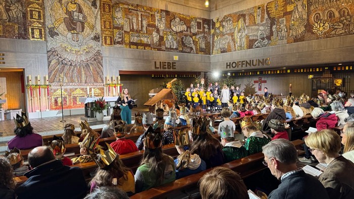 Ein festlicher Gottesdienst mit einem Chor, der in einem prächtig geschmückten, verzierten Saal mit den Aufschriften „Liebe“ und „Hoffnung“ auftritt.