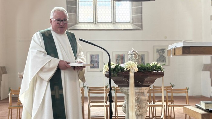 Priester hält Messingkanne in Kirche