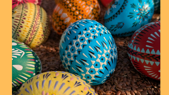 Bunt bemalte Ostereier, arrangiert auf einem Bett aus braunem Papierstreu.