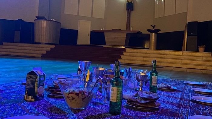 In der Christuskirche ist eine Decke ausgebreitet, auf der weiße Teller und Besteck und eine Flasche zu sehen sind.