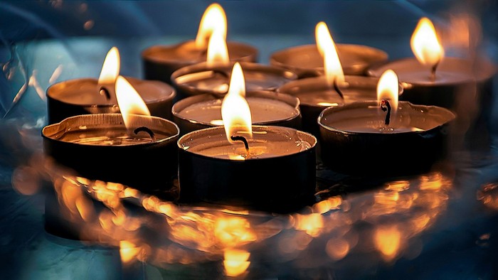 Mehrere brennende Teelichter in Metallhaltern, die in einer Reihe angeordnet sind