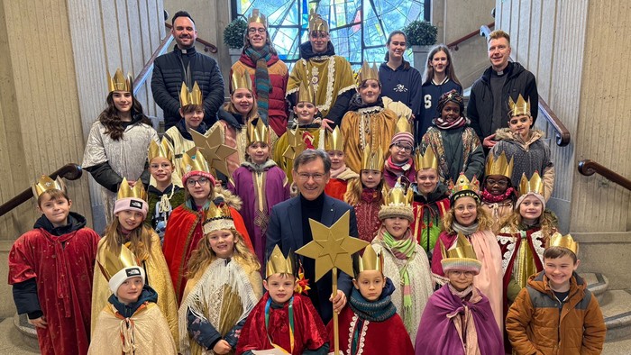 Gruppe von Kindern, verkleidet als Heilige Drei Könige, mit Erwachsenen, die für ein festliches Urlaubsfoto posieren.