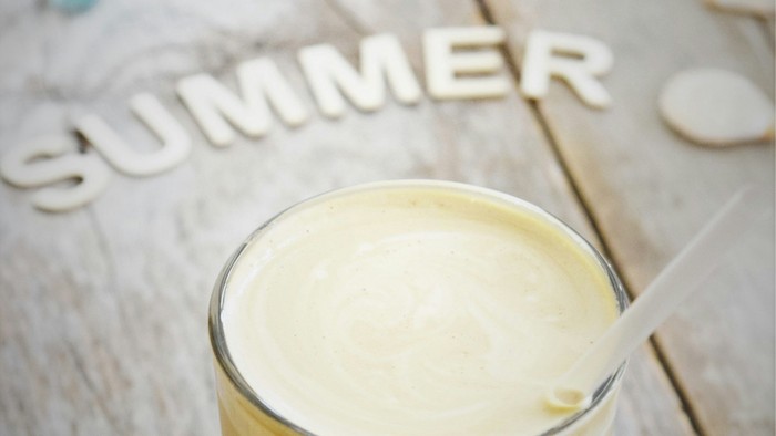 A refreshing iced drink in a glass with summer-themed wooden letters and decorative ice cubes.