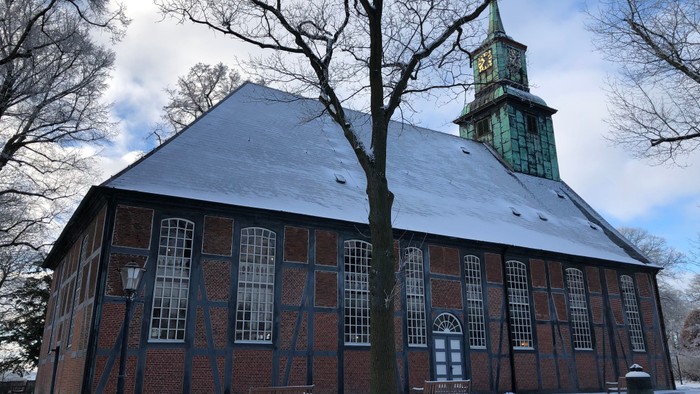 Eislige Winterlandschaft mit Backsteinkirche und hohem Turm.