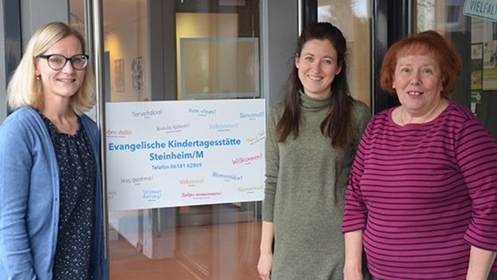 Drei Frauen stehen vor einer evangelischen Kindertagesstätte in Steinheim und lächeln in die Kamera.