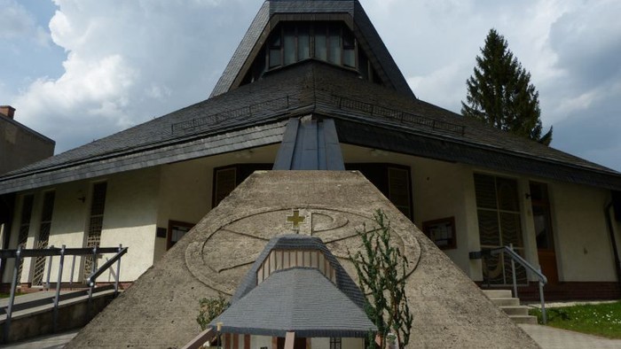 Miniaturmodell einer Kirchenreplik, ausgestellt vor einem größeren, echten Kirchengebäude.