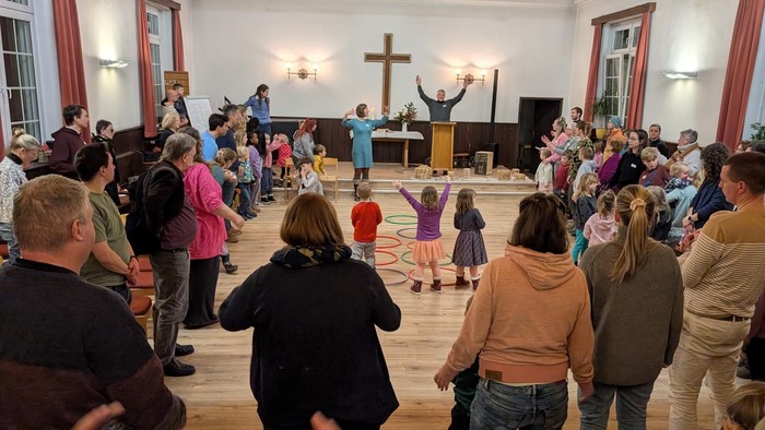 Die Gruppe nimmt an einem Reigentanz oder einer Aktivität in einer Kirche oder einem Gemeindehaus teil.
