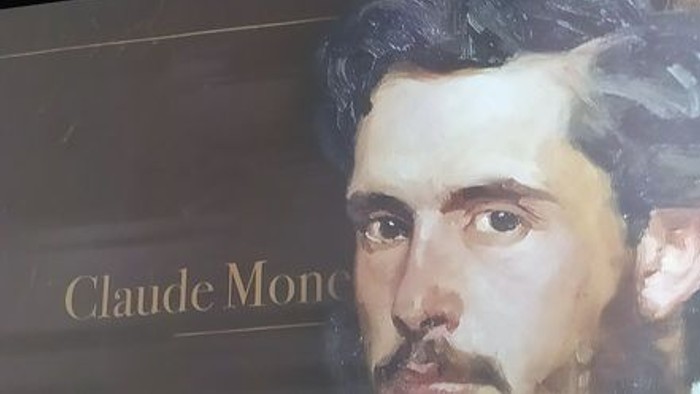 Porträt von Claude Monet mit Namensschild darunter, vor dunklem Hintergrund ausgestellt.