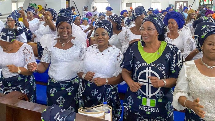 Gruppe von Frauen in traditioneller Kleidung, die den Welt-Nigeria-Tag feiern, lächelnd und begeistert klatschend.