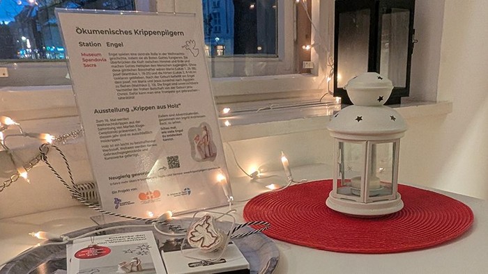 Info Krippenpilgern mit Flyer, Engel-Stempel und Laterne vorm Fenster