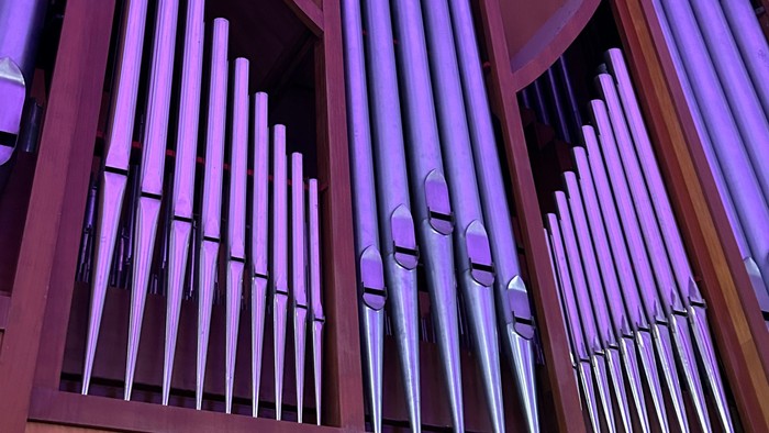 Eine Nahaufnahme einer großen Pfeifenorgel mit mehreren polierten Metallpfeifen, die in einem symmetrischen, gestuften Design angeordnet sind.