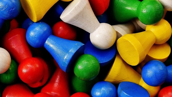 Bunte Kunststoff-Reißzwecken in verschiedenen Formen und leuchtenden Farben, die durcheinander verstreut sind.