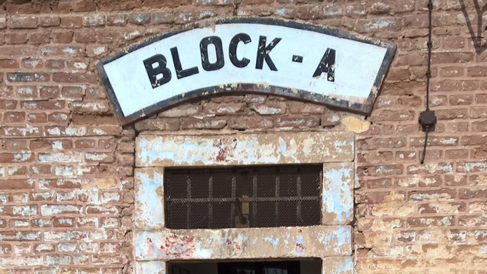 Ein Ziegelsteingebäude-Eingang mit der Aufschrift „Block-A“, einem vergitterten Fenster und verwitterter Beschilderung.