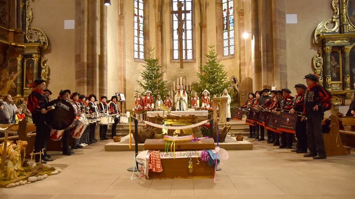Ein festlicher Gottesdienst in traditioneller Tracht mit einem geschmückten Altar und einem musikalischen Ensemble, das auftritt.