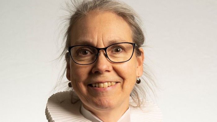 En kvinde med hvid krage og briller.