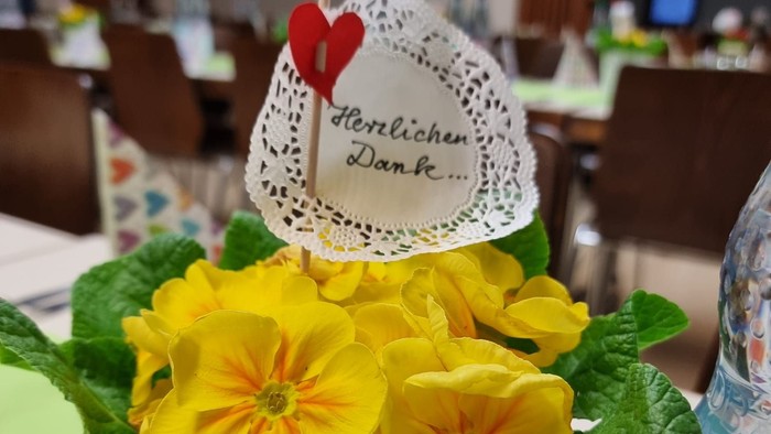 Gelbe Frühlingsblumen in einem Topf mit kleinem Herz‑Schild ‚Herzlichen Dank‘.
