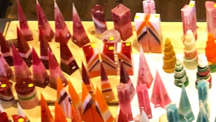 Bunte handgefertigte Holzfiguren und Kerzenhalter für Weihnachten künstlerisch arrangiert ausgestellt.