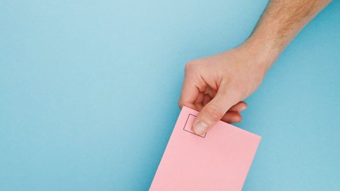 Hand steckt rosafarbenen Brief in Kartonbox