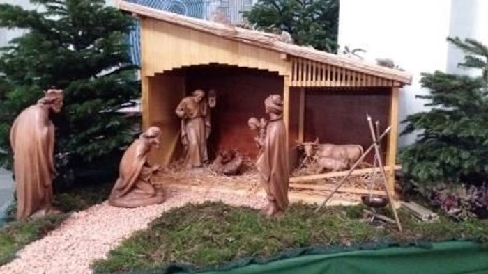 Die Szene zeigt eine Krippe mit mehreren Figuren vor einem kleinen Stall.