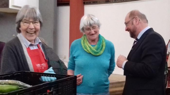 Eine Gruppe von Menschen steht um einen Tisch mit frischem Gemüse.