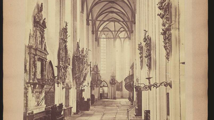 Historisches Kathedraleninneres mit verzierten gotischen Bögen, Kerzenhaltern und religiösen Verzierungen.