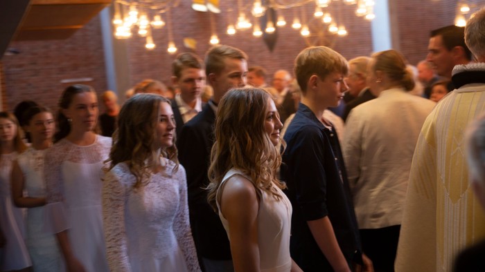 En gruppe af festdeltagere danser og samler sig i et lysende og indelukket rum.