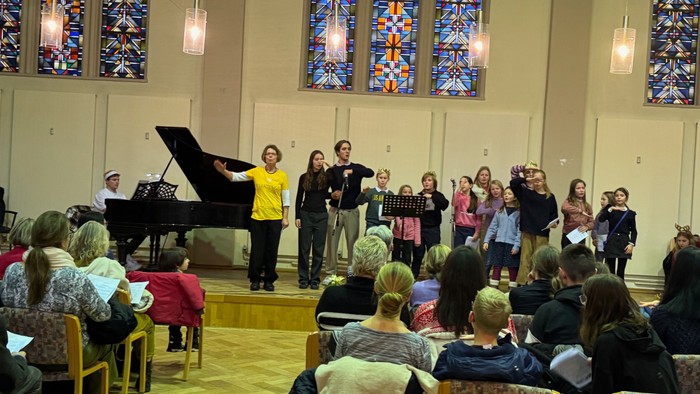 Eine Gruppe von Menschen singt und spielt in einer Kirche, während ein Publikum zusieht.