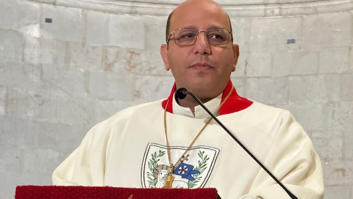 Ein Geistlicher in liturgischer Kleidung steht auf einer Kanzel und hält eine Predigt in einer Kirche.