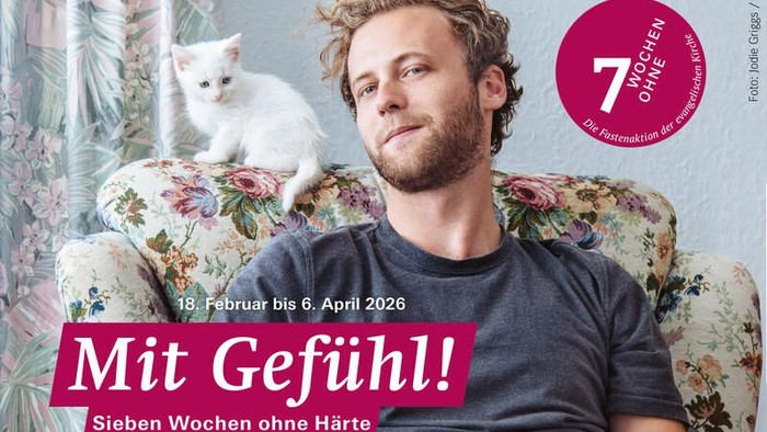 Ein Mann sitzt in einem blumigen Sessel mit einer weißen Katze und bewirbt die Ausstellung *„Mit Gefühl! Sieben Wochen ohne Härte“* vom 18. Februar bis 6. April 2026.