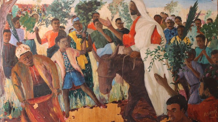 A painting depicts Jesus riding a donkey, surrounded by a crowd of people.