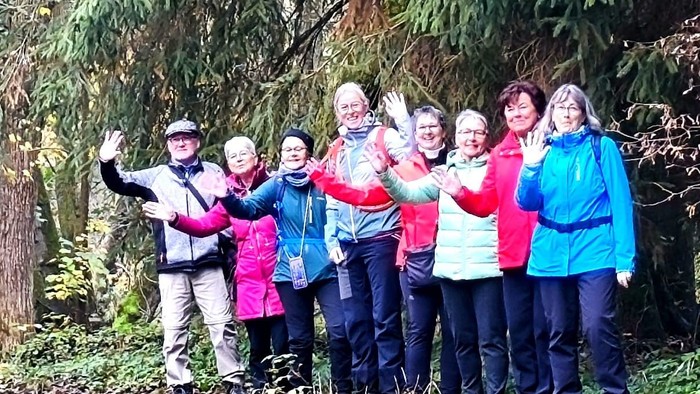 Eine Gruppe von Menschen, die fröhlich in einem Wald posieren, eingehüllt in warme Kleidung und lächelnd.